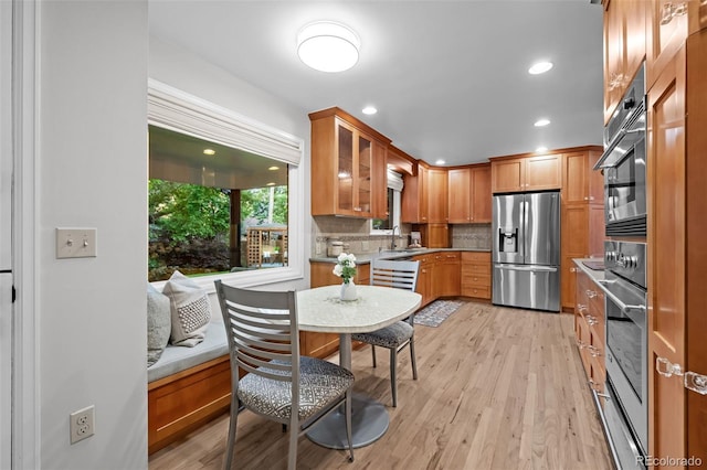 2684 Taft Ct, Lakewood, CO 80215 - kitchen with appliances with stainless steel finishes, a sink, glass insert cabinets, decorative backsplash, and light wood-style flooring