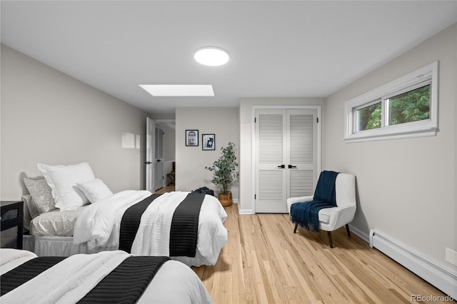 2684 Taft Ct, Lakewood, CO 80215 - bedroom featuring a baseboard heating unit, a skylight, a closet, light wood-type flooring, and baseboards