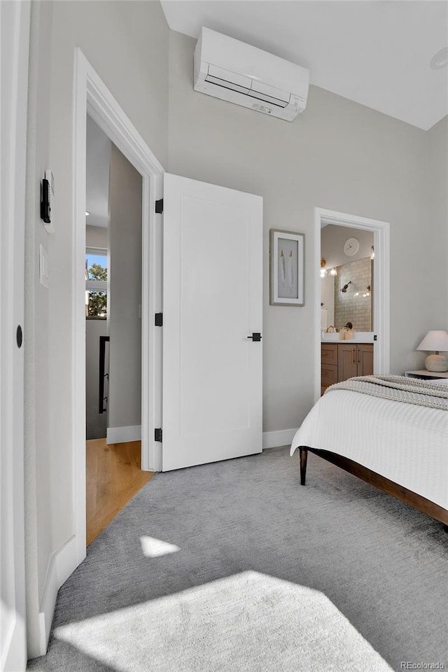 bedroom featuring ensuite bathroom, light carpet, and a wall mounted AC