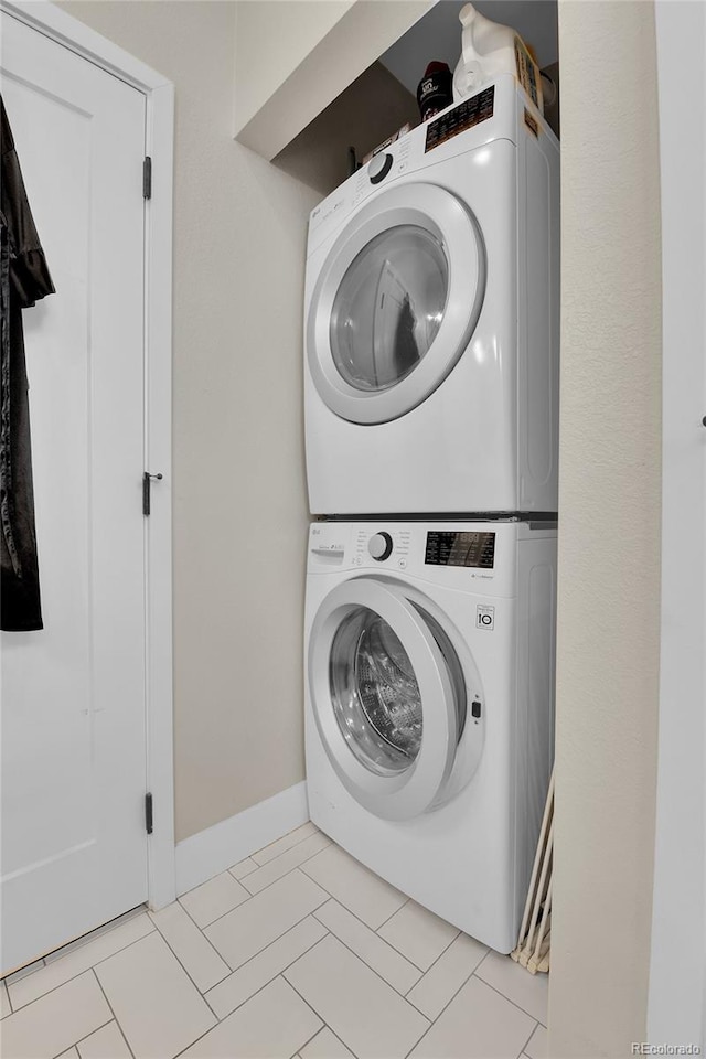 laundry room with stacked washing maching and dryer and light tile patterned flooring