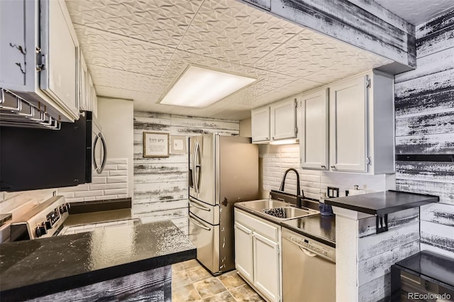 kitchen with appliances with stainless steel finishes, sink, decorative backsplash, and white cabinets