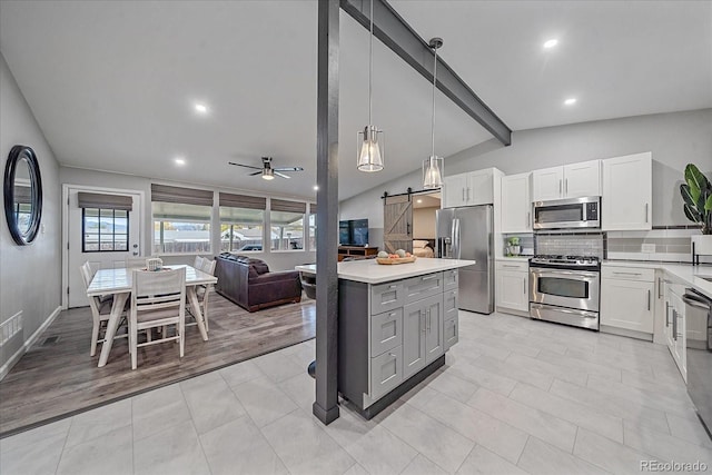 kitchen with backsplash, open floor plan, lofted ceiling with beams, a barn door, and stainless steel appliances