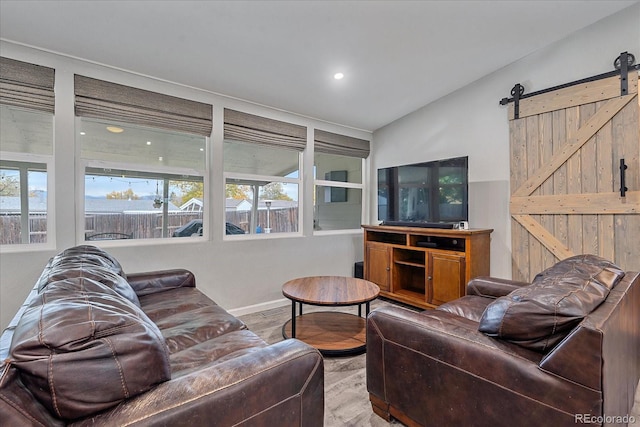 living area with plenty of natural light, baseboards, lofted ceiling, and a barn door