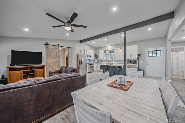 dining space with light wood-type flooring, lofted ceiling with beams, recessed lighting, a barn door, and ceiling fan