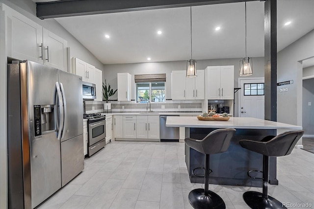 kitchen with backsplash, light countertops, appliances with stainless steel finishes, a kitchen breakfast bar, and white cabinetry