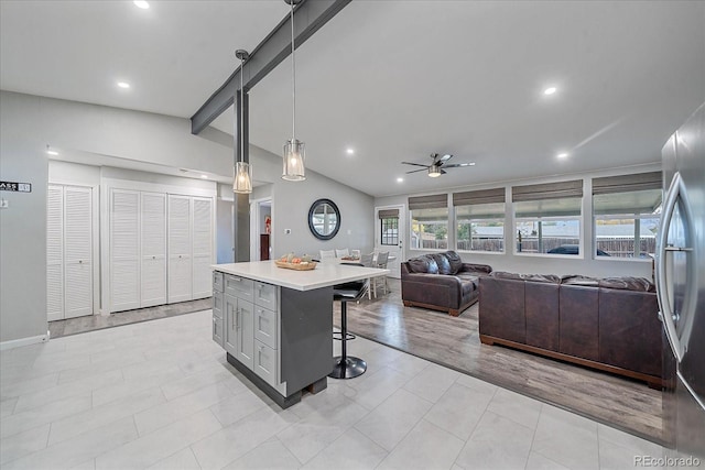 kitchen featuring lofted ceiling with beams, a kitchen breakfast bar, open floor plan, light countertops, and ceiling fan