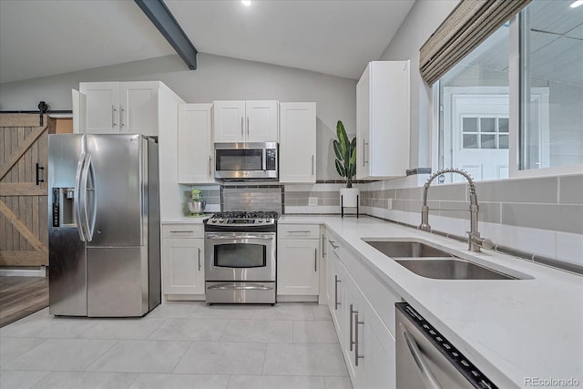 kitchen featuring lofted ceiling with beams, a sink, white cabinets, appliances with stainless steel finishes, and tasteful backsplash