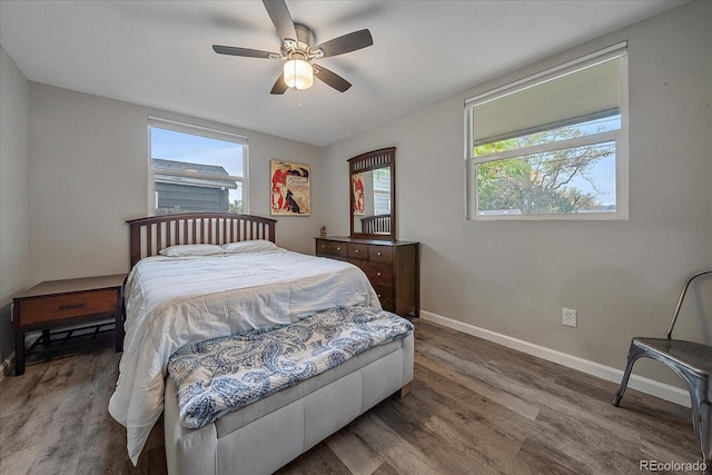 bedroom with multiple windows, ceiling fan, baseboards, and wood finished floors