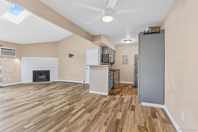 unfurnished living room with a fireplace, a baseboard radiator, wood-type flooring, and ceiling fan