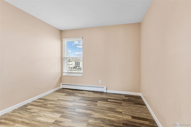 unfurnished room featuring a baseboard heating unit and wood-type flooring