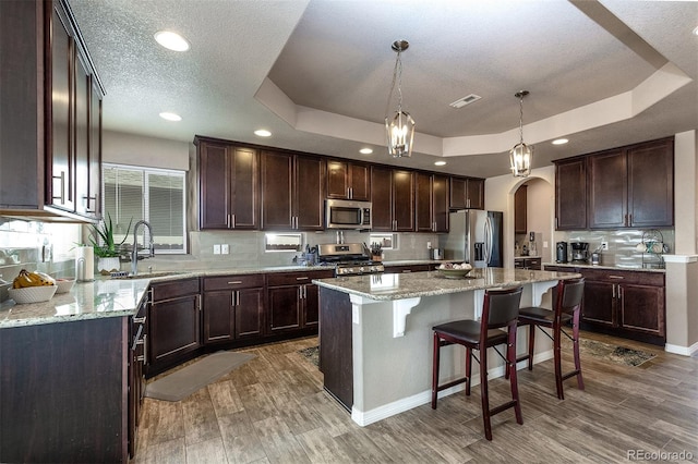 kitchen featuring a sink, visible vents, arched walkways, a tray ceiling, and appliances with stainless steel finishes