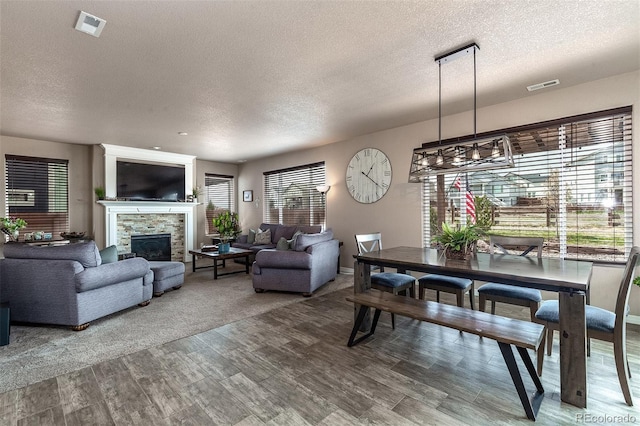 dining area with a textured ceiling, visible vents, and wood finished floors