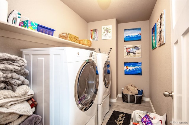 laundry area with baseboards, separate washer and dryer, laundry area, and wood finished floors