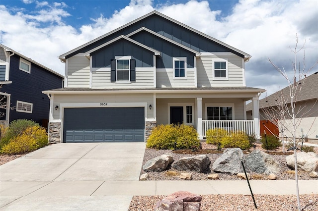 view of front of property featuring covered porch, an attached garage, stone siding, driveway, and board and batten siding