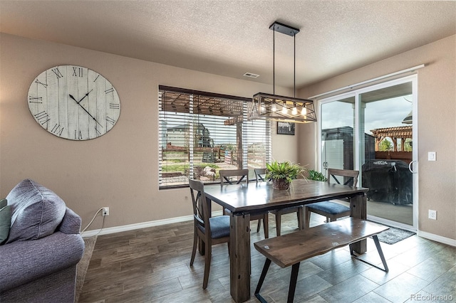 dining space featuring a textured ceiling, baseboards, dark wood-style flooring, an inviting chandelier, and visible vents