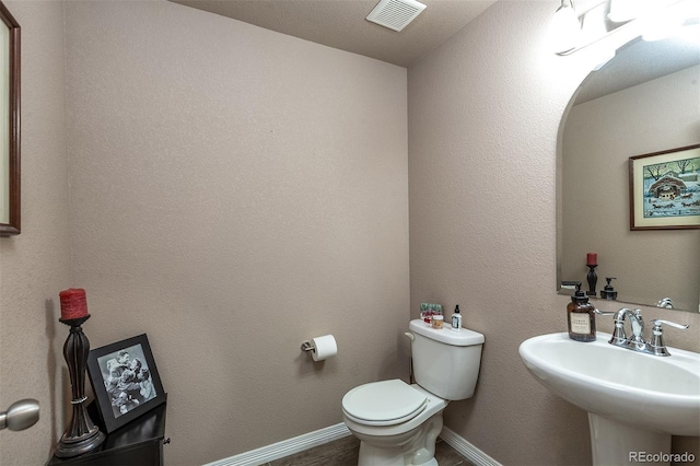 bathroom featuring toilet, baseboards, visible vents, and a sink