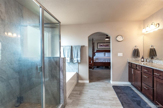 ensuite bathroom featuring wood finished floors, vanity, a shower stall, connected bathroom, and a bath