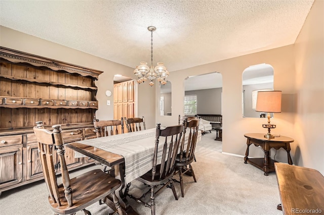 3150 Lane Ct, Boulder, CO 80305 - dining area with arched walkways, light carpet, a chandelier, a textured ceiling, and baseboards