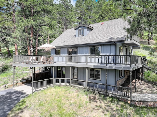 30221 Marge Ln, Evergreen, CO 80439 - view of front of property with roof with shingles, a deck, board and batten siding, a patio area, and view of scattered trees