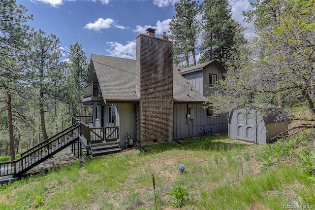 30221 Marge Ln, Evergreen, CO 80439 - rear view of property featuring board and batten siding, a shingled roof, a shed, and a chimney