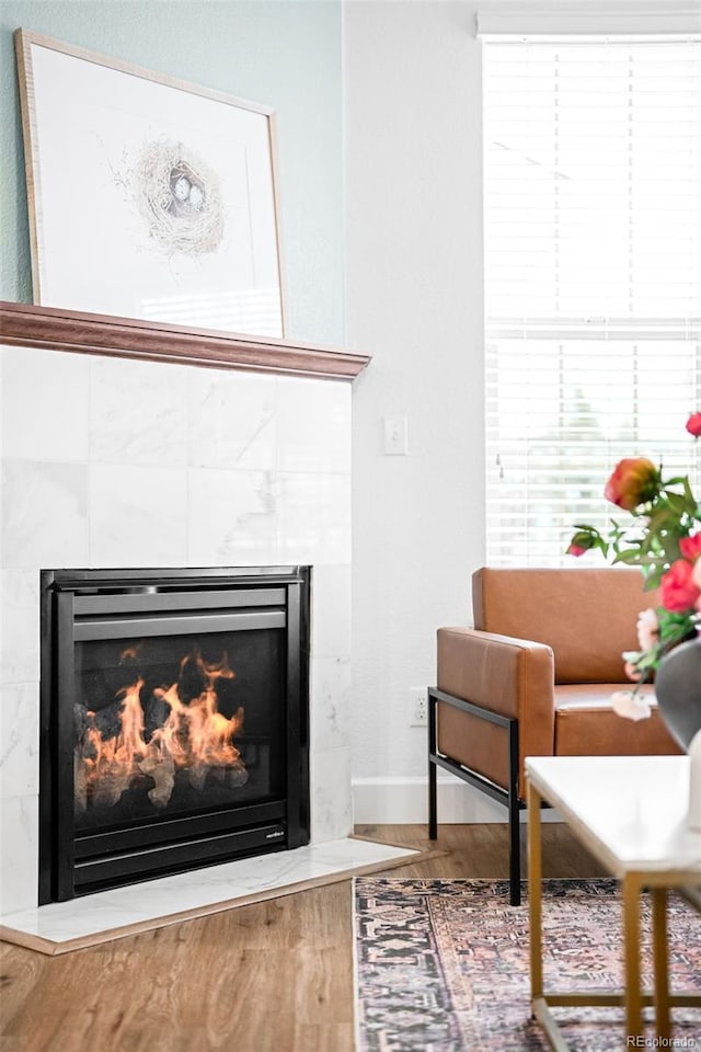 interior details featuring a tiled fireplace, baseboards, and wood finished floors