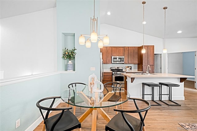 dining area with baseboards, light wood-type flooring, and high vaulted ceiling