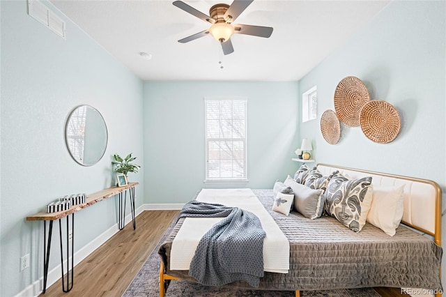 bedroom with ceiling fan, visible vents, baseboards, and wood finished floors