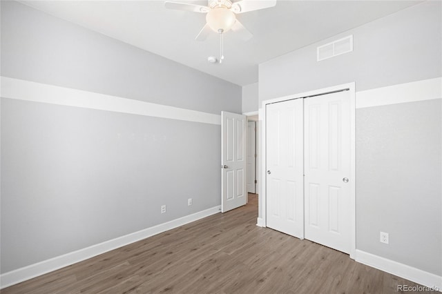 unfurnished bedroom with wood finished floors, visible vents, baseboards, ceiling fan, and a closet