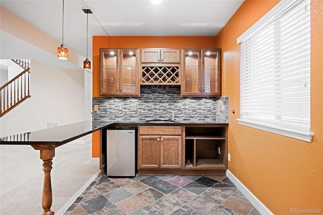 bar with a sink, refrigerator, indoor wet bar, decorative backsplash, and baseboards