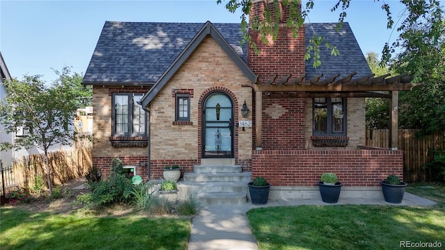 tudor-style house featuring a front yard and a pergola