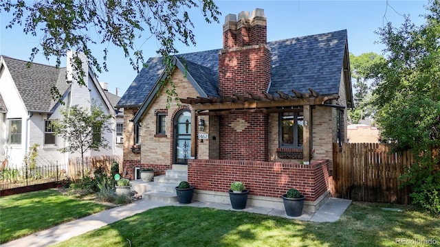 tudor home featuring a pergola and a front lawn