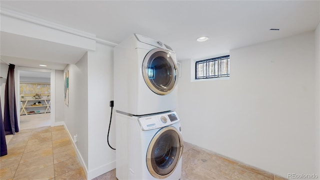 clothes washing area featuring light tile patterned floors and stacked washer and dryer