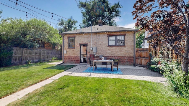 back of property with a yard and a patio area