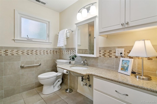 4803 N Weber St, Colorado Springs, CO 80907 - bathroom featuring tile patterned floors, tile walls, tiled shower, and wainscoting