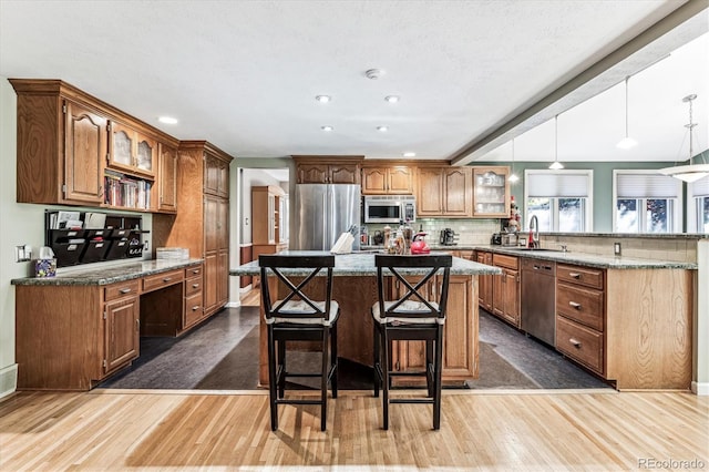 kitchen featuring an island with sink, appliances with stainless steel finishes, a breakfast bar area, and light wood-type flooring