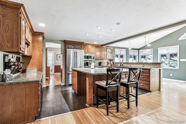 kitchen with kitchen peninsula, light wood-type flooring, a center island, and stainless steel appliances