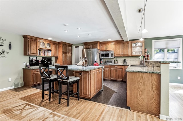 kitchen featuring a kitchen breakfast bar, sink, a center island with sink, beamed ceiling, and stainless steel appliances