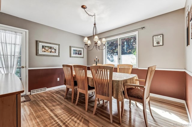 dining space with wood-type flooring and an inviting chandelier