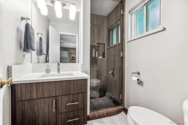 bathroom featuring toilet, an enclosed shower, and vanity