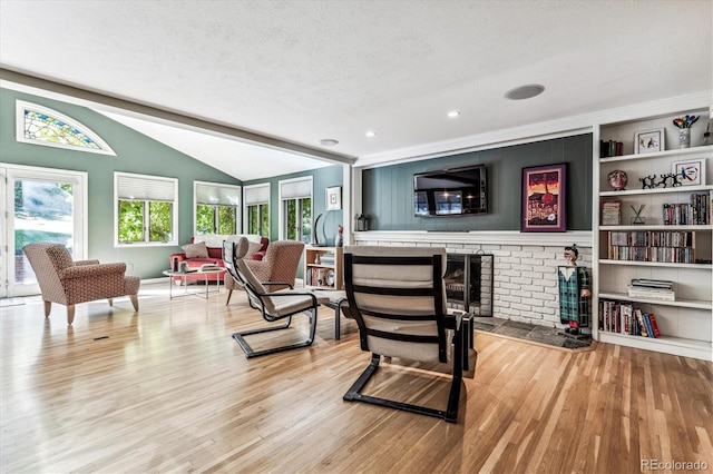 living room featuring a textured ceiling, vaulted ceiling, hardwood / wood-style floors, and a fireplace