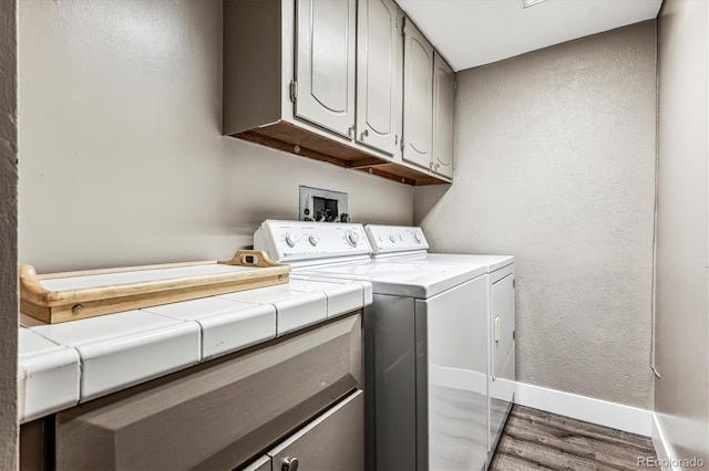 laundry room with wood-type flooring, separate washer and dryer, and cabinets