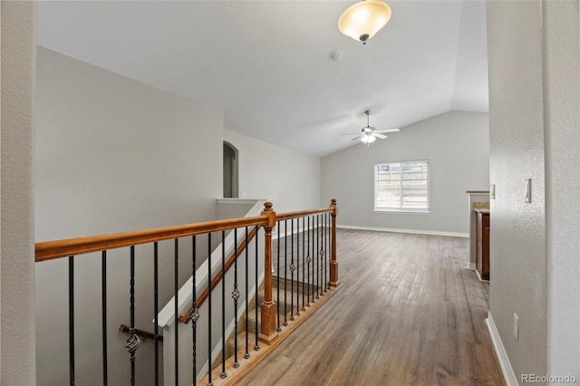 corridor with hardwood / wood-style floors and vaulted ceiling