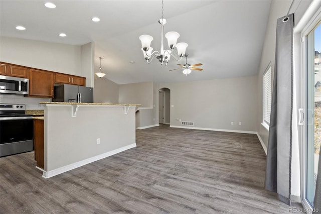 kitchen with stainless steel appliances, a kitchen bar, decorative light fixtures, lofted ceiling, and dark wood-type flooring