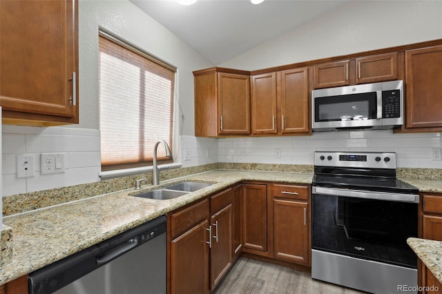 kitchen with stainless steel appliances, sink, backsplash, and vaulted ceiling