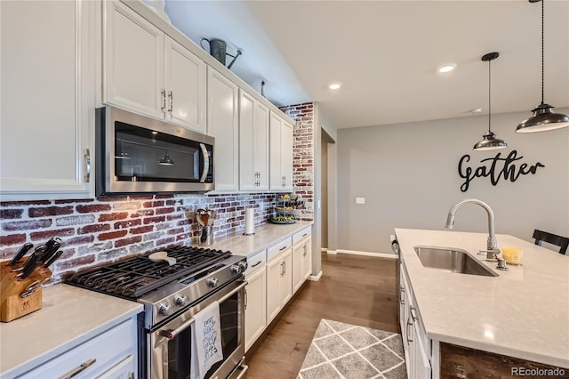 kitchen with appliances with stainless steel finishes, sink, white cabinets, and hardwood / wood-style floors