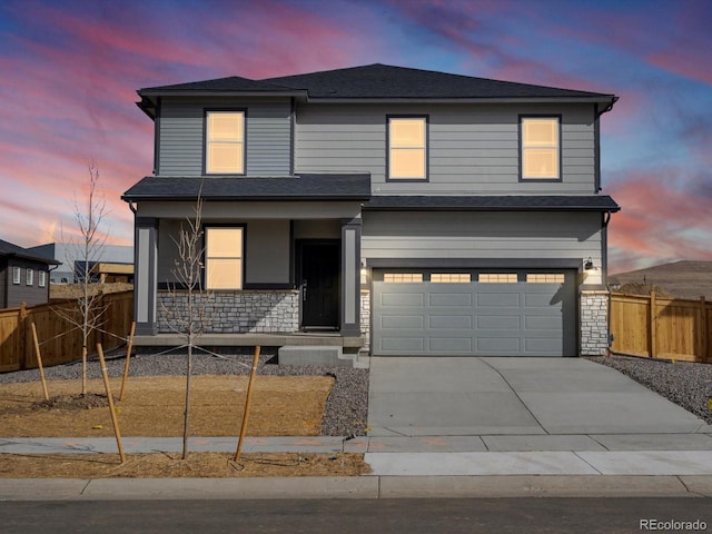 traditional-style home with fence, a porch, an attached garage, concrete driveway, and stone siding