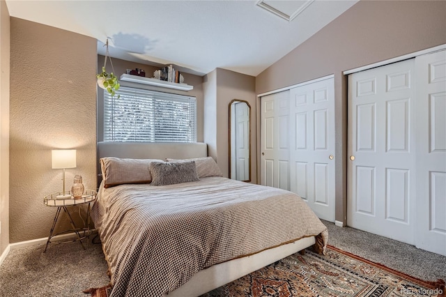 carpeted bedroom with lofted ceiling and two closets