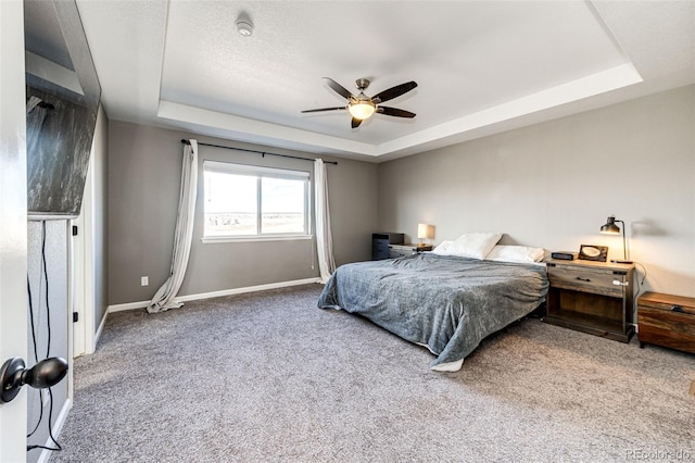 bedroom with carpet, baseboards, a tray ceiling, and a ceiling fan