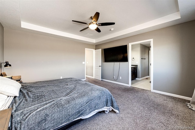 carpeted bedroom with ensuite bath, ceiling fan, baseboards, and a raised ceiling