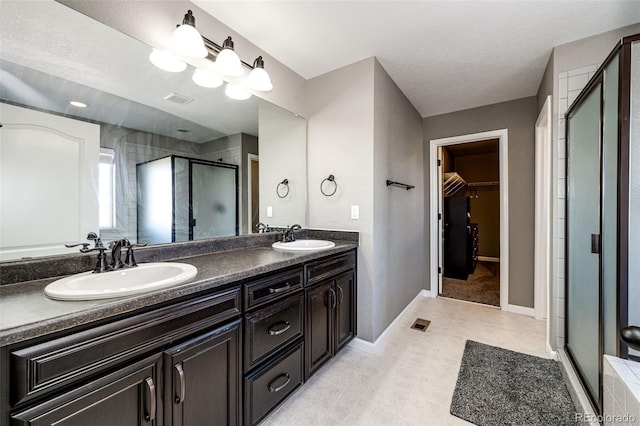 full bathroom featuring a shower stall, a spacious closet, visible vents, and a sink